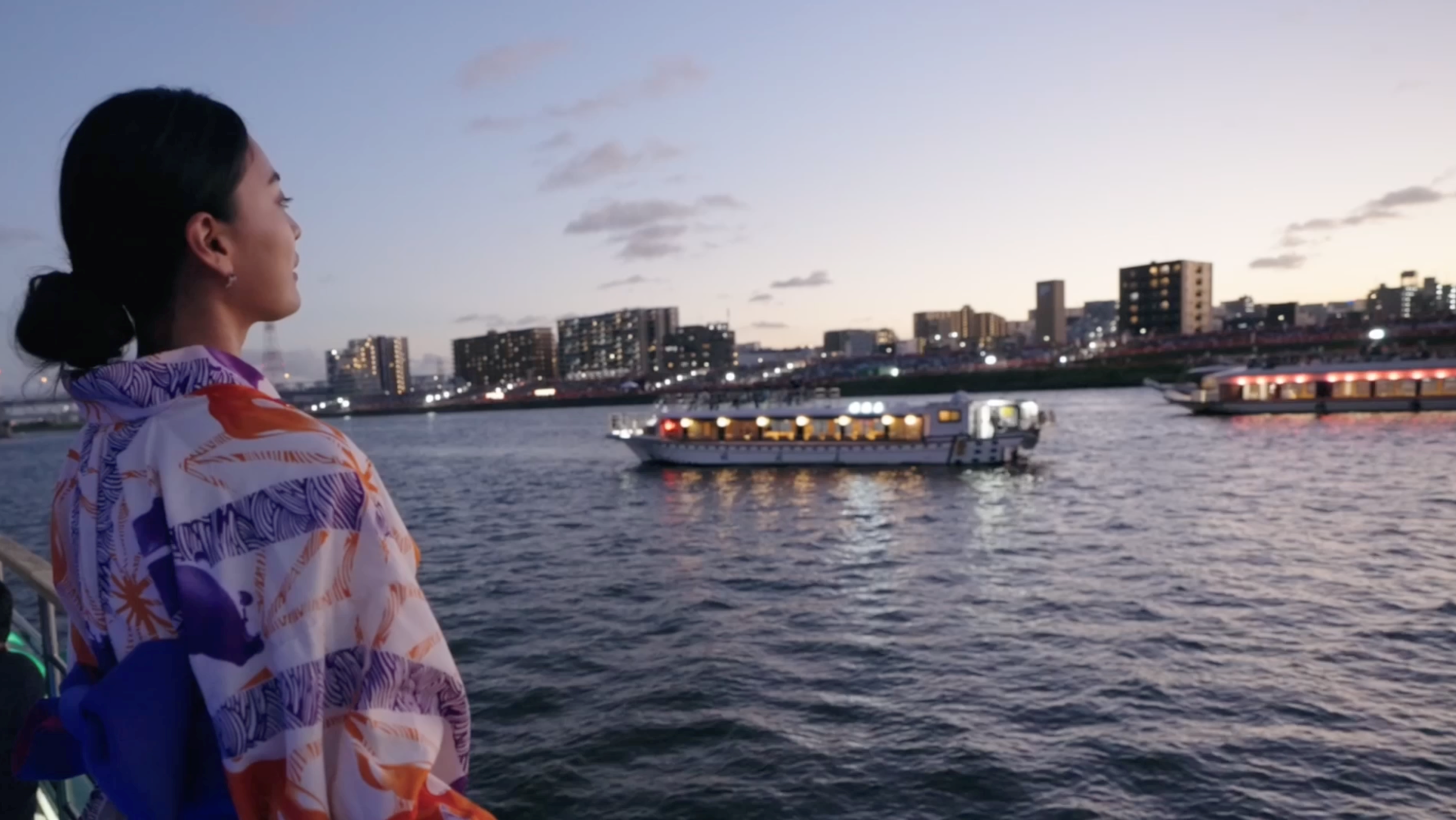屋形船を眺める浴衣姿の女性。