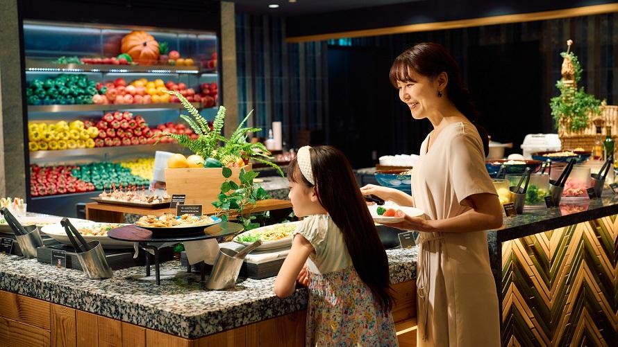 さまざまな料理が並ぶブッフェで料理を取る母娘