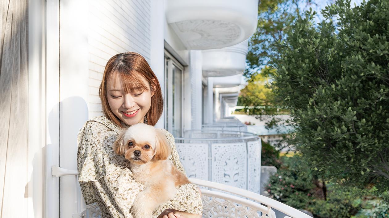 グランドプリンスホテル新高輪のドッグフレンドリールームのバルコニーで女性が犬を抱っこして微笑んでいる。