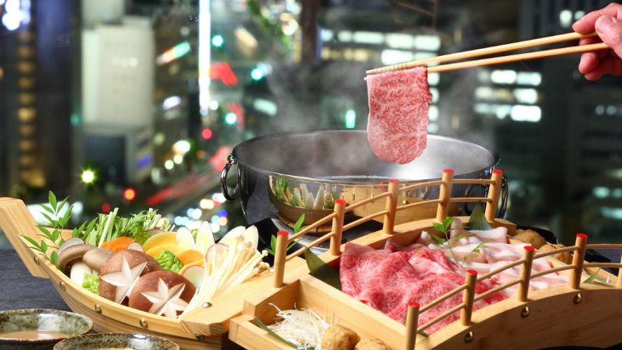 夜景をバックに飛騨牛を鍋に入れている様子