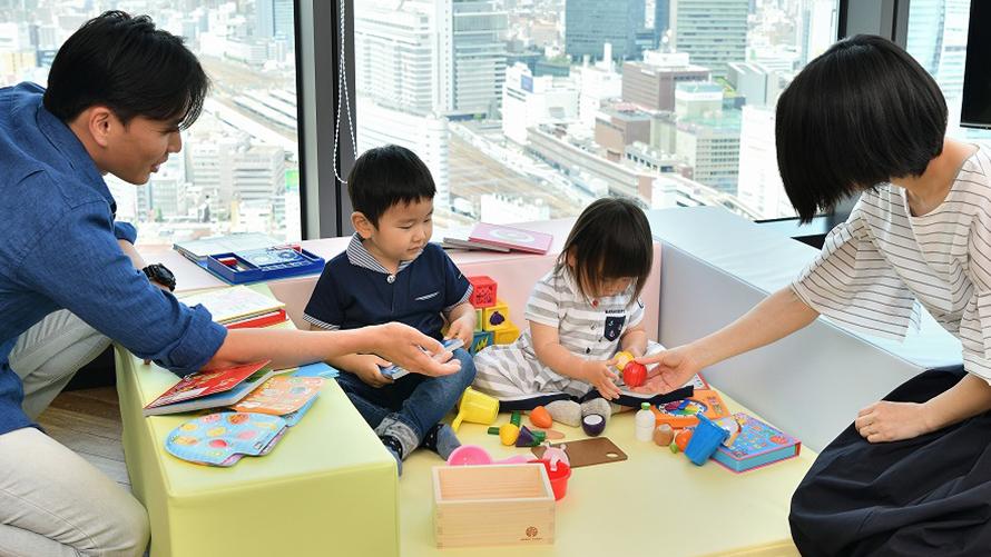 プレイマットの上で子供と両親が遊んでいる