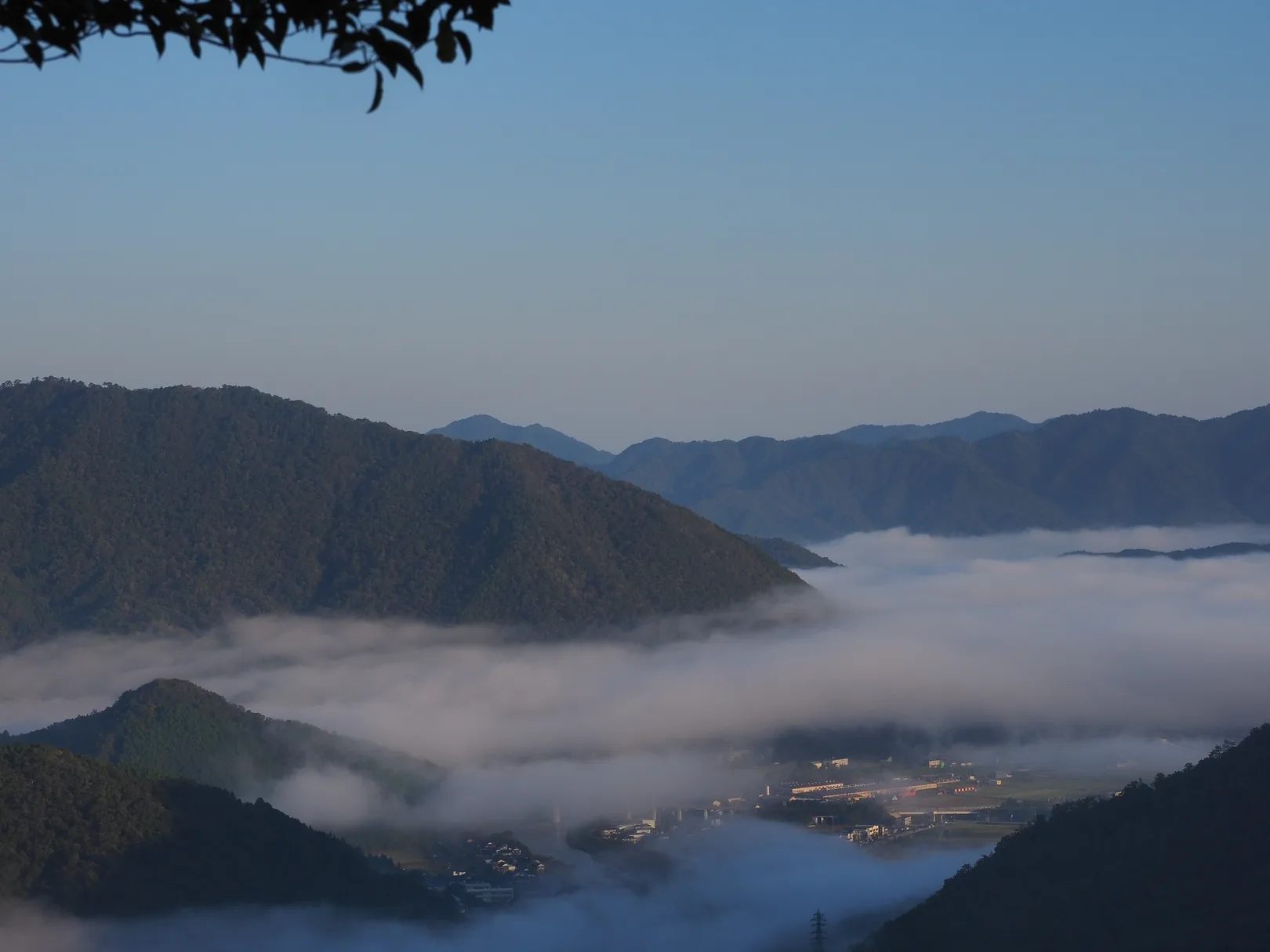 PIXTAより「朝霧が晴れていく山あいの町と雲海」