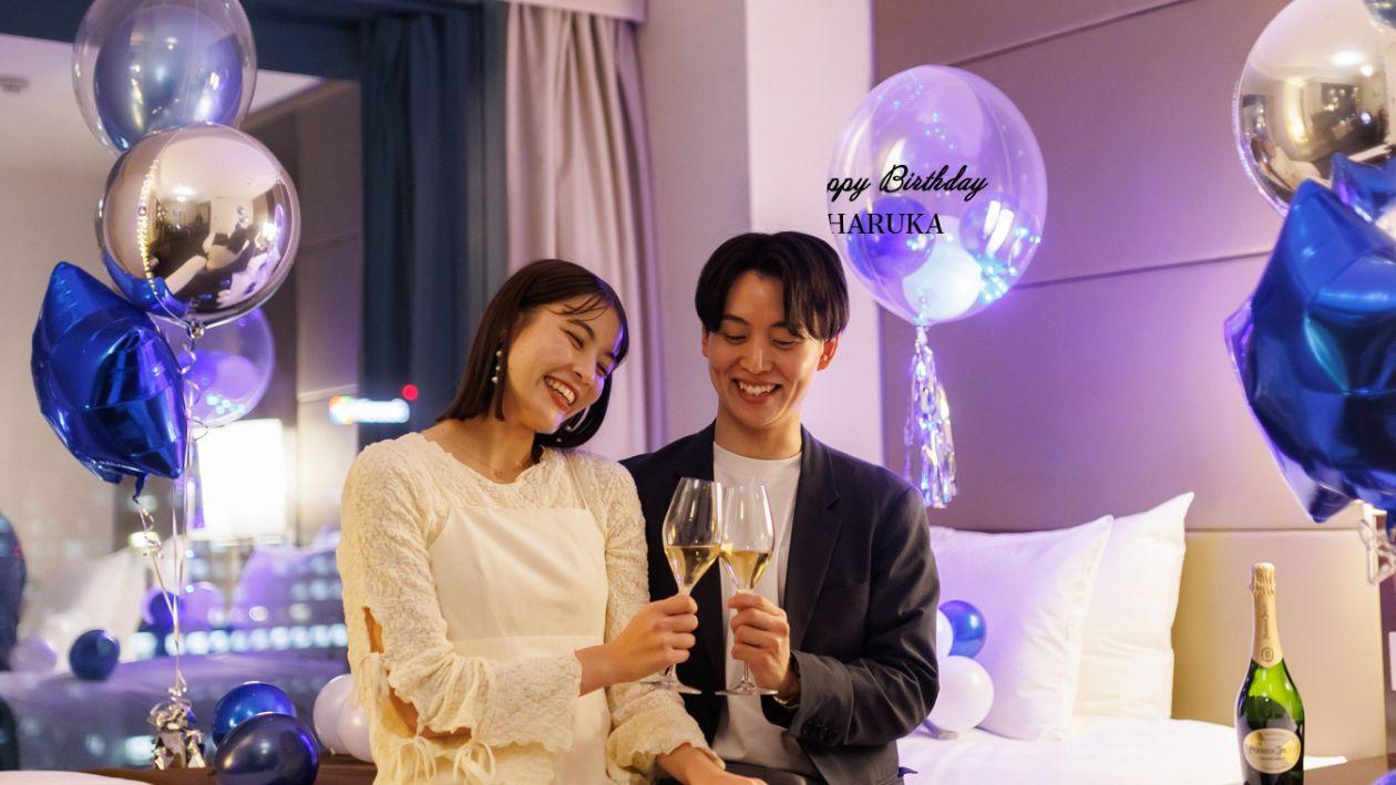 バルーンで飾られたお部屋で乾杯する男女。バルーンにはハッピーバースデーのメッセージ入り。